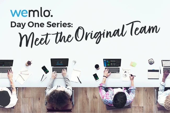 Four people work at a desk with laptops, notebooks, and smartphones. The text above reads, “wemlo: Day One Series: Meet the Original Team. View is from above on a white background. Four people work at a desk with laptops, notebooks, and smartphones. The text above reads, “wemlo: Day One Series: Meet the Original Team. View is from above on a white background.