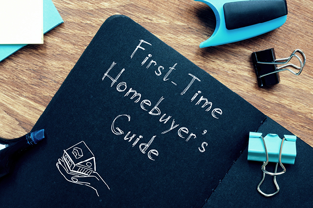 Open notebook with First-Time Homebuyers Guide written on a black page, alongside blue and black stationery items, including a clip, pen, and binder clip, on a wooden desk. Open notebook with First-Time Homebuyers Guide written on a black page, alongside blue and black stationery items, including a clip, pen, and binder clip, on a wooden desk.