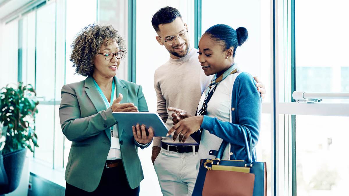 Happy couple talking to business professional in an office looking at an iPad