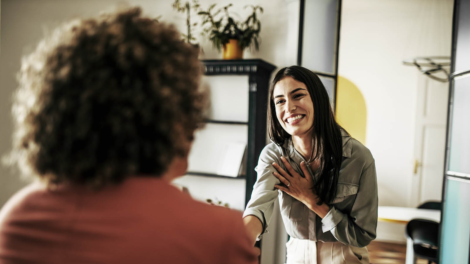 Person in an office setting shaking hands during a friendly, face-to-face client meeting.