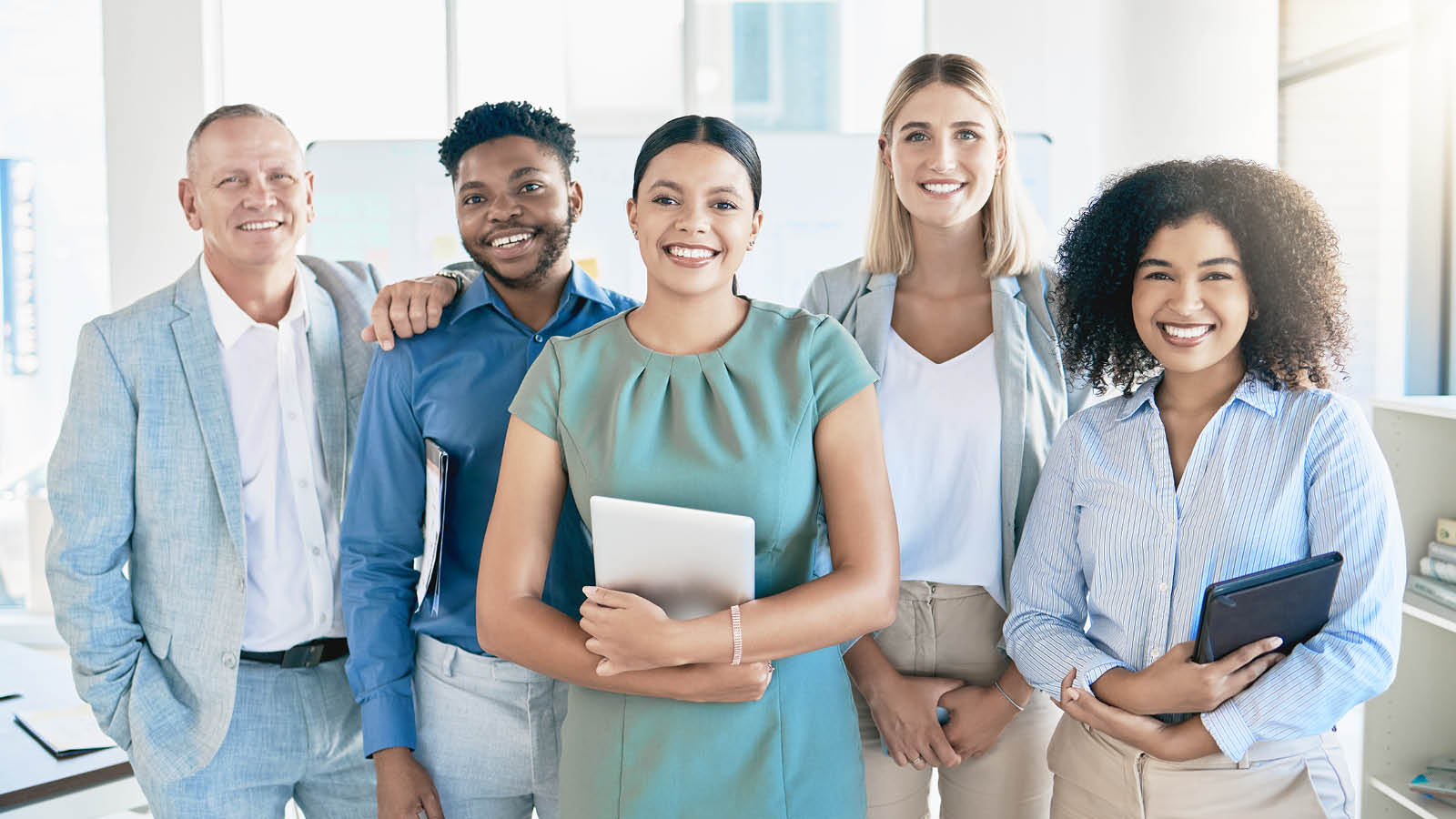 Group of five business professionals standing together in an office, representing the mortgage team involved in the home loan process.